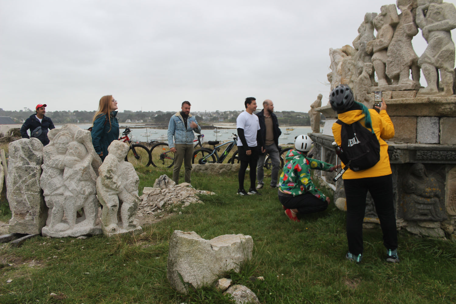 groupe d'adultes entrain de jouer dehors face à une oeuvre en pierre